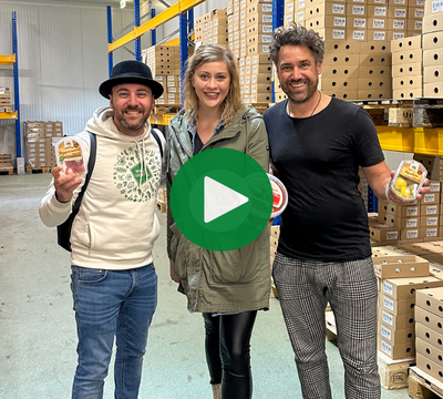 3 lachende Personen in einem Lagerraum mit Käsemacherprodukten mit Blick in die Kamera