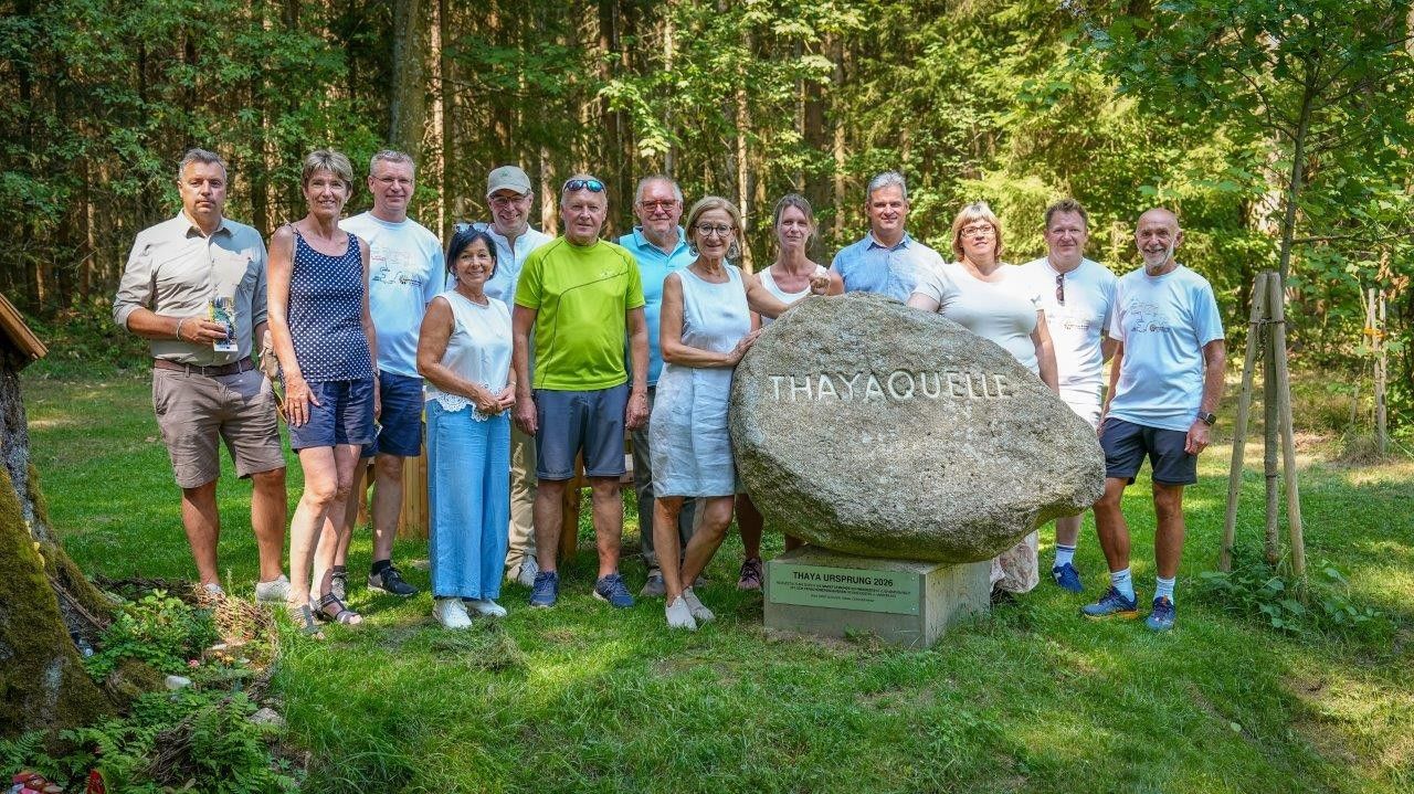 Gruppenfoto im Wald vor großem Stein mit Aufschrift Thaya Ursprung