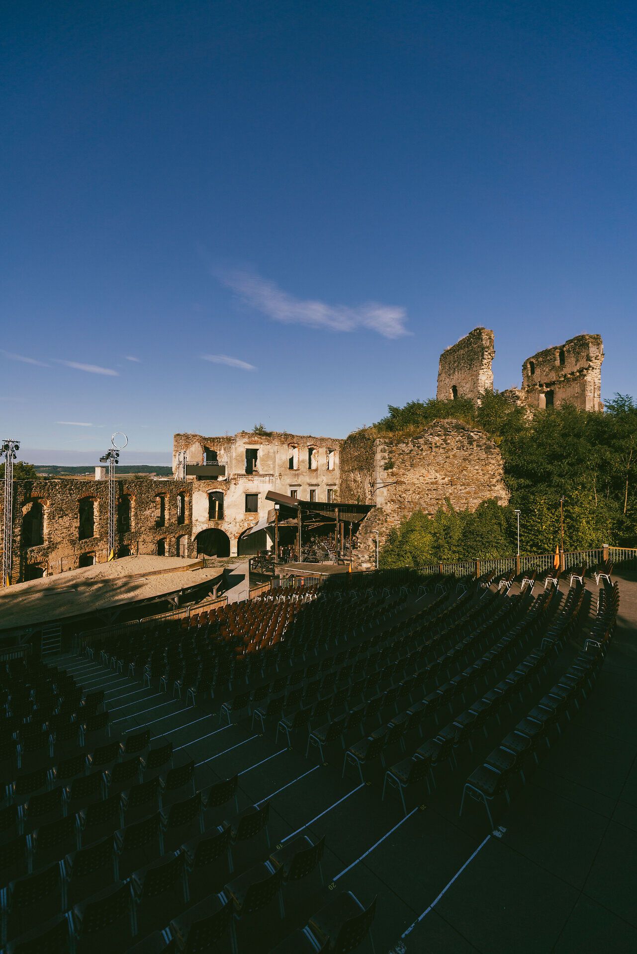 Die beeindruckenden Ruinen der Burg Gars erheben sich majestätisch gegen den klaren blauen Himmel. Umgeben von einer malerischen Kulisse, bietet der Ort eine perfekte Atmosphäre für das Theaterfest, wo Kultur und Geschichte aufeinandertreffen. Die leeren Sitzreihen laden die Besucher ein, in eine Welt voller Geschichten und Emotionen einzutauchen.