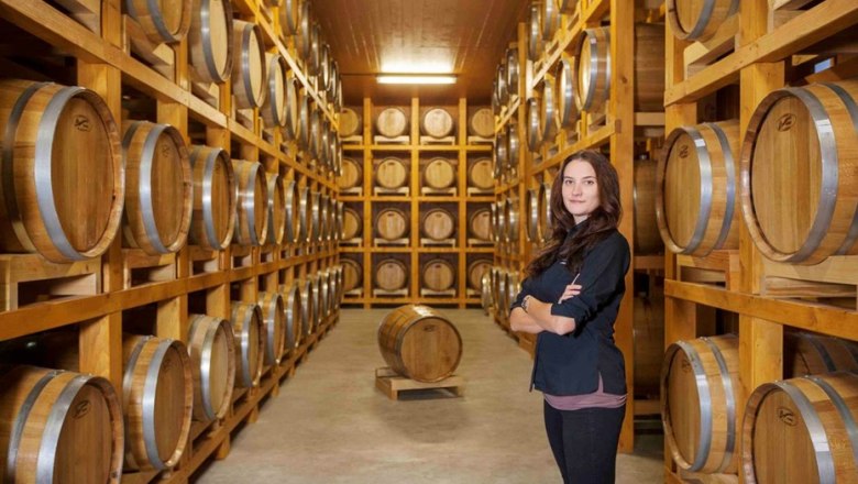Eine Frau steht in einem Lagerraum mit vielen Holzfässern auf Regalen.