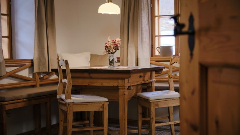 Gemütliche Küche mit Holztisch, Stühlen und Blumenstrauß auf dem Tisch.