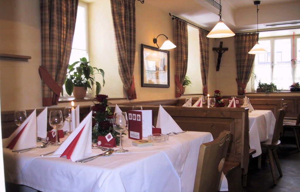 Gemütliches Restaurant mit gedeckten Tischen, Holzmöbeln und karierten Vorhängen.