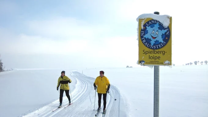 Zwei Personen beim Langlaufen auf der schneebedeckten Spielbergloipe in Bad Traunstein.