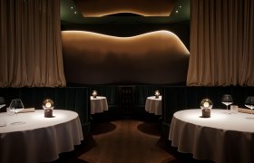 Elegantes Restaurant mit runden Tischen, weißen Tischdecken und gedämpfter Beleuchtung.