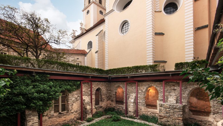 Innenhof des Stifts Altenburg mit Brunnen und Kirchturm im Hintergrund.
