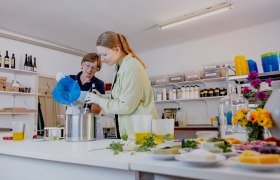 Zwei Personen beim Seifenherstellen in einer Werkstatt.