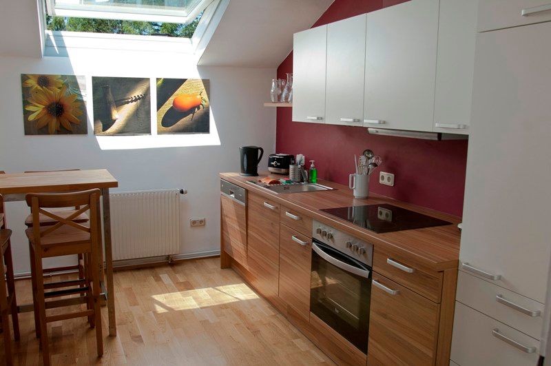 Moderne Küche mit Holzarbeitsplatte, Dachfenster und Wandbildern.