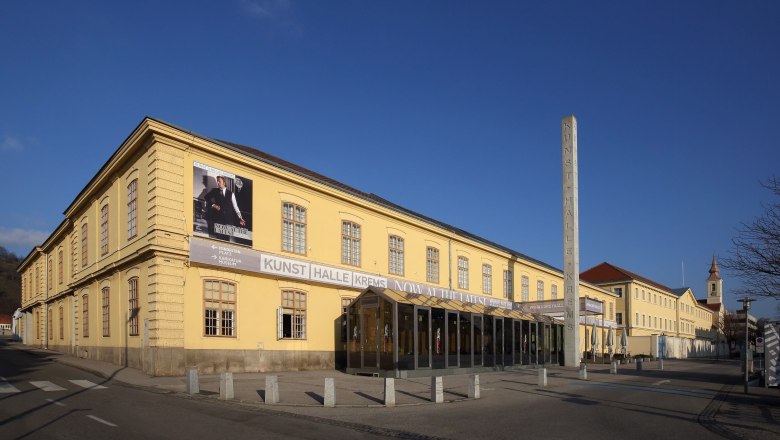 Au&szlig;enansicht der Kunsthalle Krems mit gelbem Geb&auml;ude und blauem Himmel.