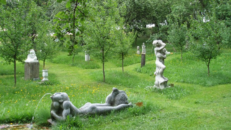 Skulpturen in einem grünen Garten mit Bäumen.