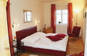 Gemütliches Schlafzimmer mit rotem Bett und Dekor.