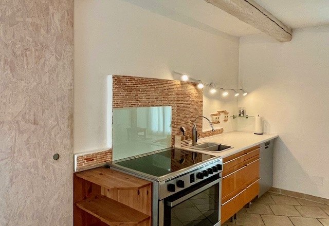 Moderne Küche mit Holzschränken, Herd, Spüle und Fliesenrückwand.