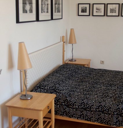 Schlafzimmer mit Doppelbett, Nachttischen und Wandbildern.
