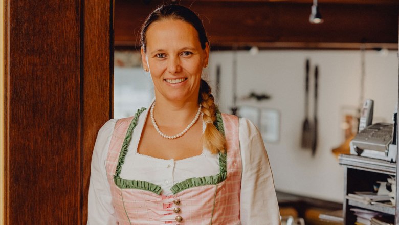 Frau in traditioneller Tracht lächelt in einem Restaurant.