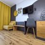Modern furnished room with yellow armchair, wooden floor, desk and wall decorations.