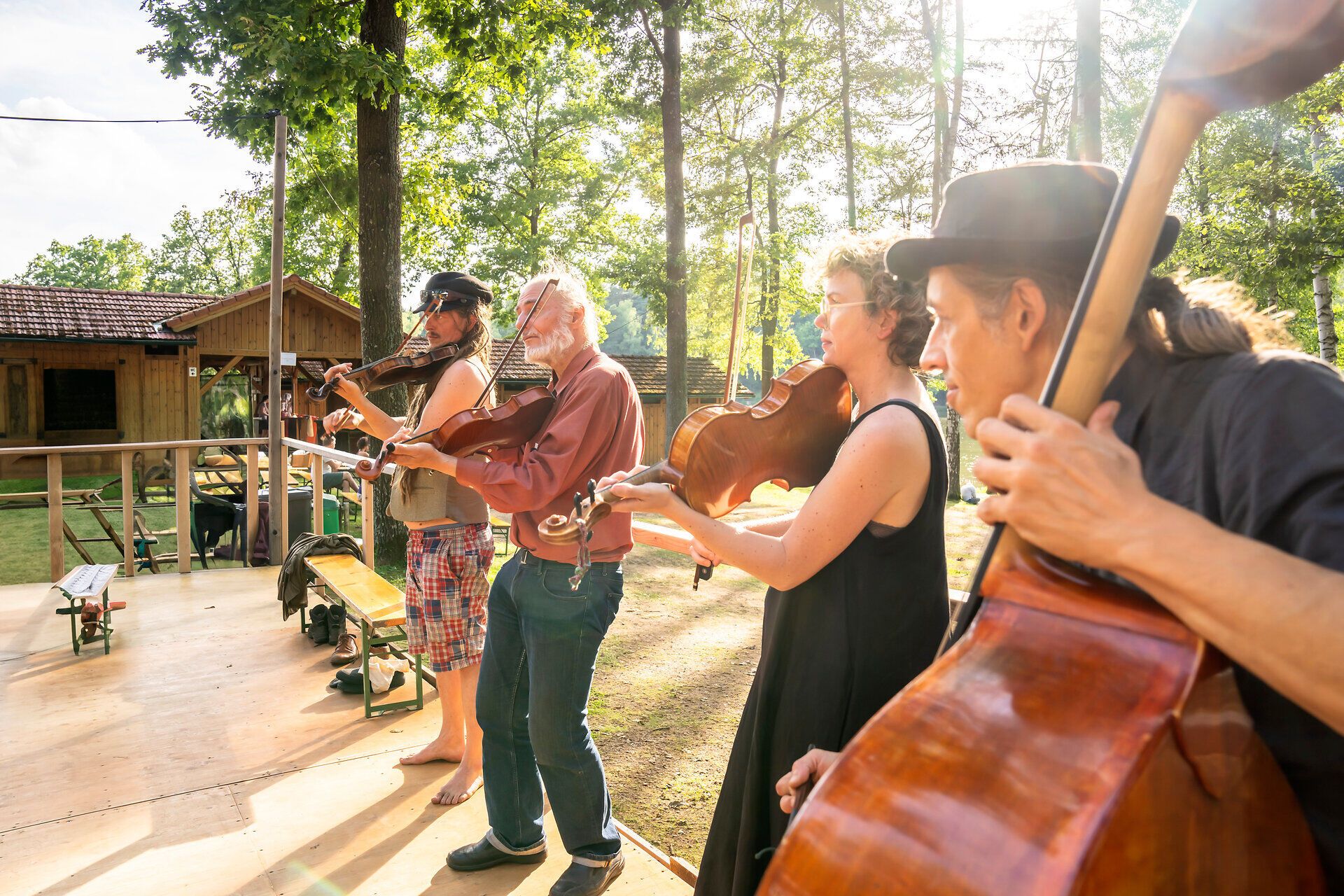 Die Klänge des Schrammel.Klang.Festivals erfüllen die Luft, während Musiker inmitten der Natur ihre Instrumente spielen. Umgeben von Bäumen und sanften Sonnenstrahlen, entsteht eine harmonische Atmosphäre, die die Besucher in ihren Bann zieht.