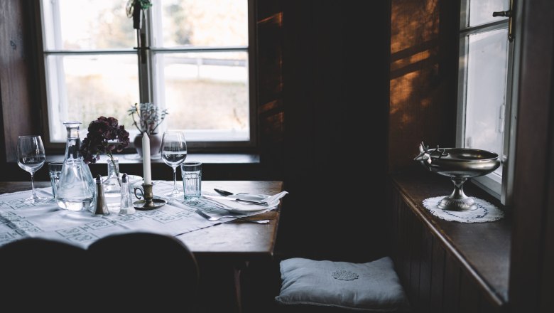 A cozy table setting in a rustic parlor with candles and wine glasses.