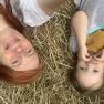 Zwei Personen liegen lächelnd auf Heu, eine erwachsene Person und ein Kind.