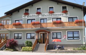 Ein traditionelles Gasthaus mit Holzbalkon und Blumenk&auml;sten.