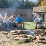 Gruppe von Kindern und einem Erwachsenen am Lagerfeuer im Freien.