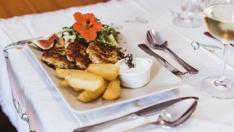 A plate of wholemeal sauerkraut loafs, potato wedges, salad and dip on a table.