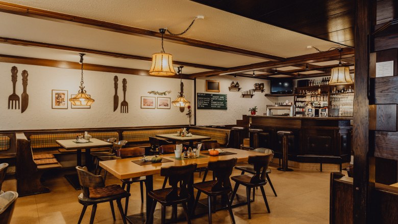 Gemütliches Wirtshaus mit Holzmöbeln, Bar und dekorativen Lampen.