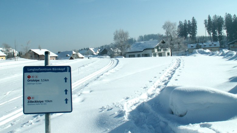 Winterlandschaft mit Langlaufloipe und Wegweiser in Bärnkopf.