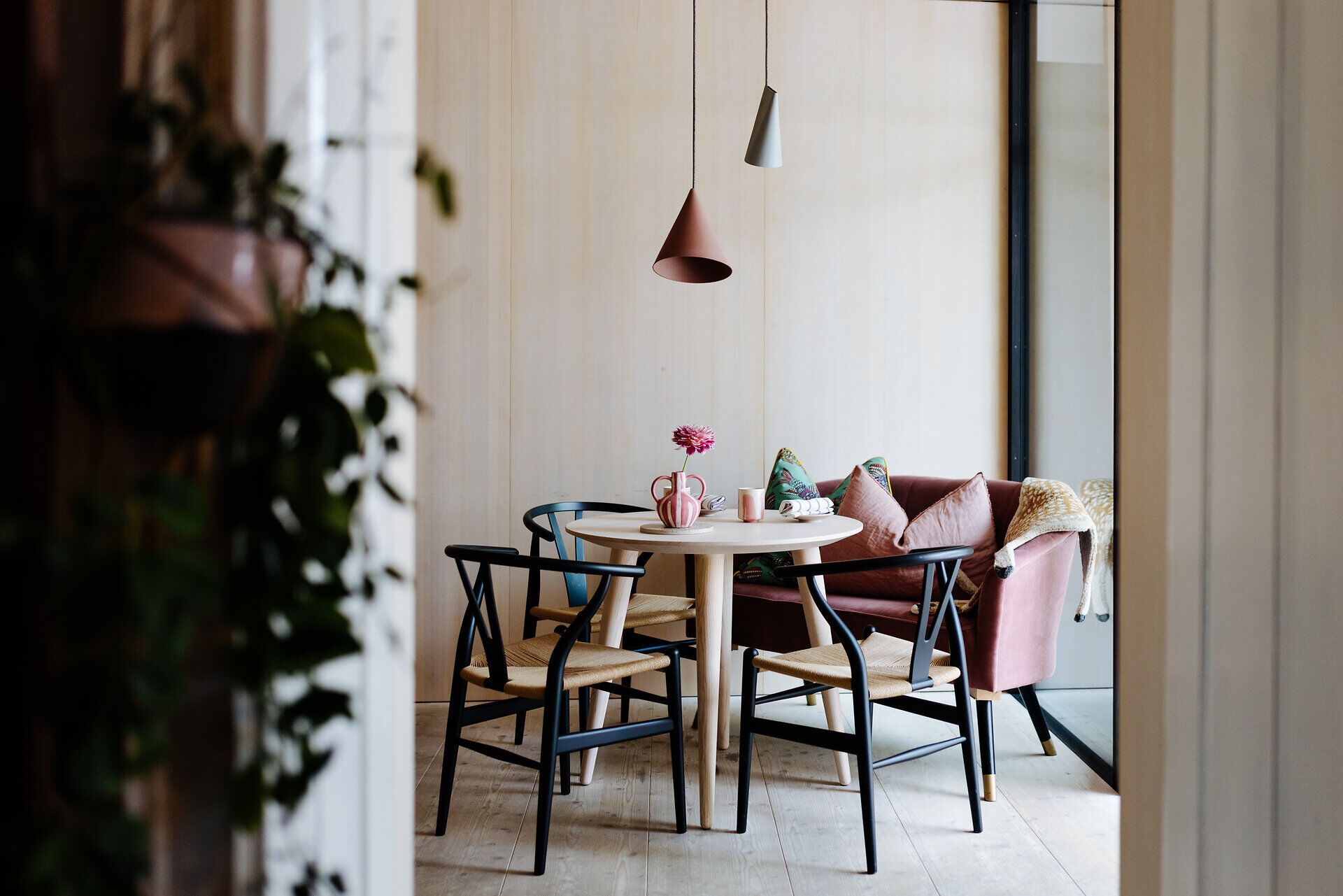 In einem einladenden Esslokal, umgeben von warmen Holztönen und gemütlichen Sitzgelegenheiten, genießen Gäste eine entspannte Atmosphäre. Ein Tisch, liebevoll gedeckt mit frischen Blumen, lädt dazu ein, die kulinarischen Köstlichkeiten der Region zu probieren. Hier wird der Sommer in vollen Zügen gefeiert, während das Licht sanft durch die Fenster strömt.