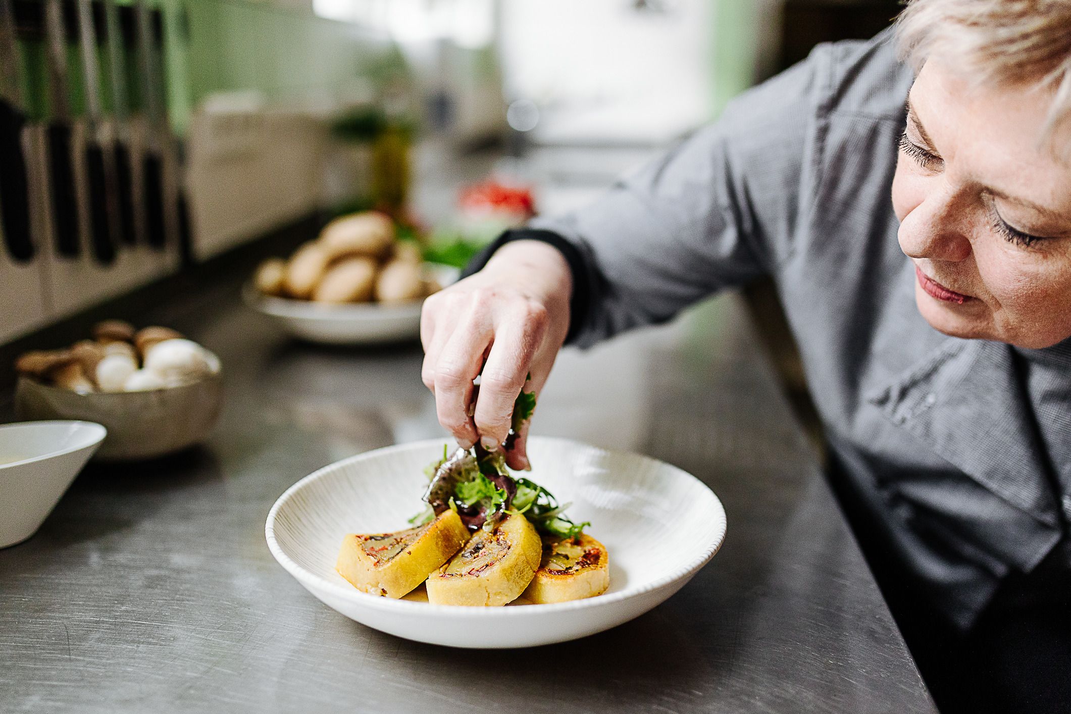 Eine Frau richtet Essen und Salat auf einem Teller an.