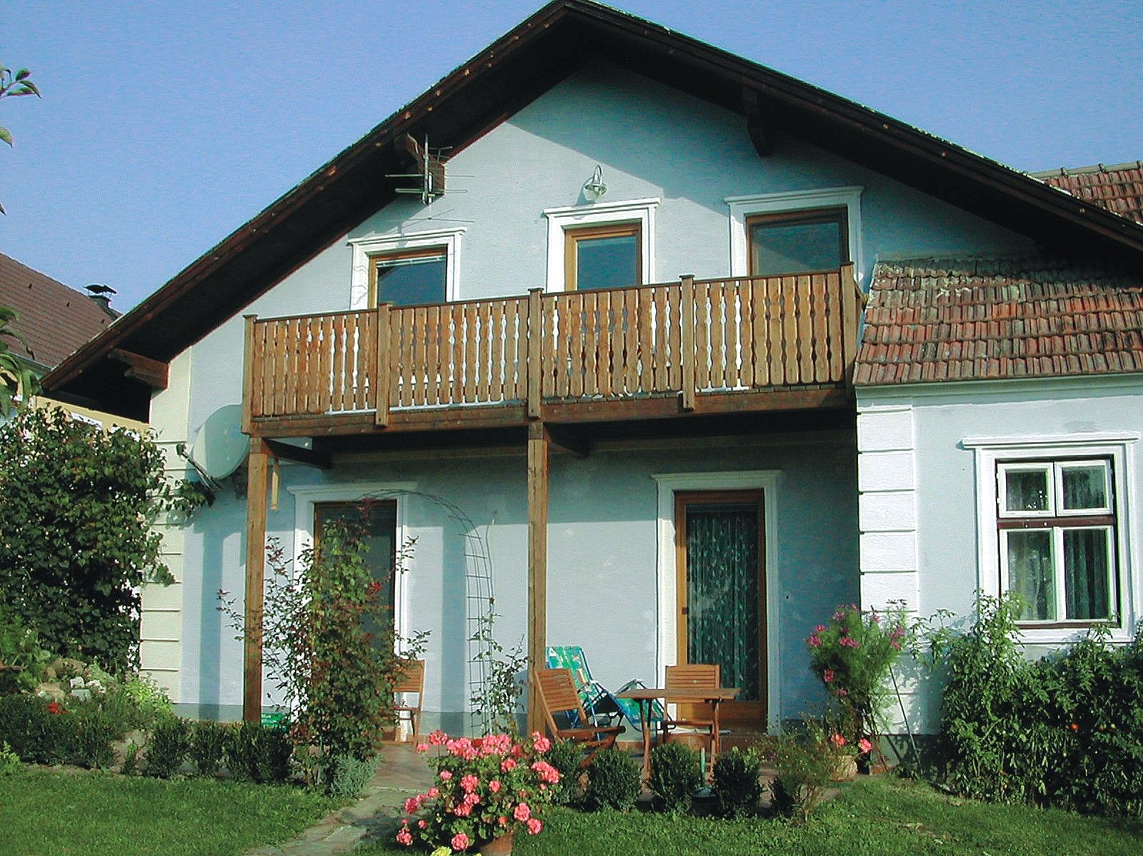 Ein traditionelles Winzerhaus mit Holzbalkon und Gartenmöbeln vor der Tür.