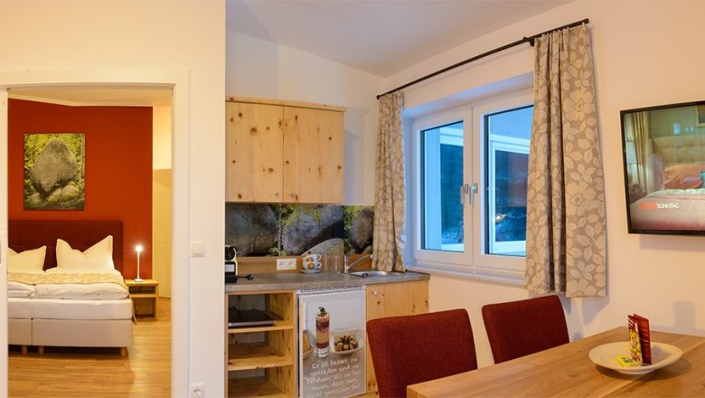 Gemütliches Zimmer mit Bett, Küchenzeile und Esstisch.