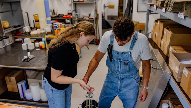 Zwei Personen ziehen Kerzen in einer Werkstatt.