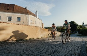 Ein Mann und eine Frau radeln bergauf entlang der Stadtmauer