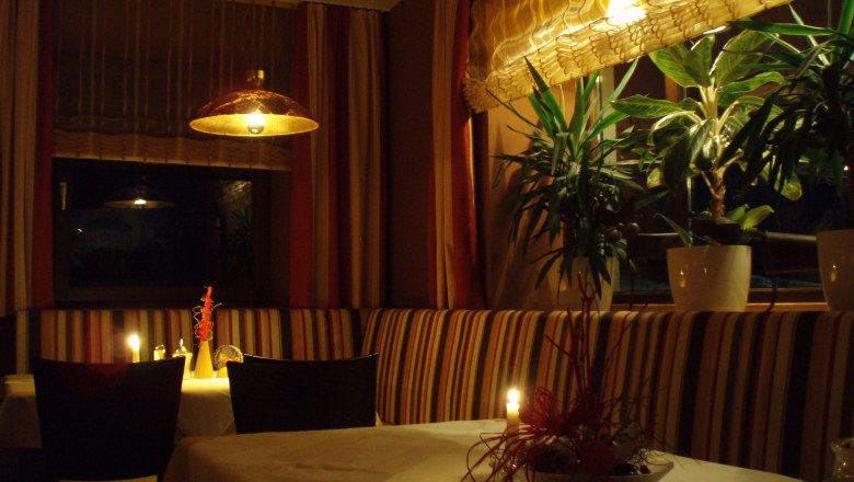 Gemütliches Restaurant mit Kerzenlicht und Pflanzen.