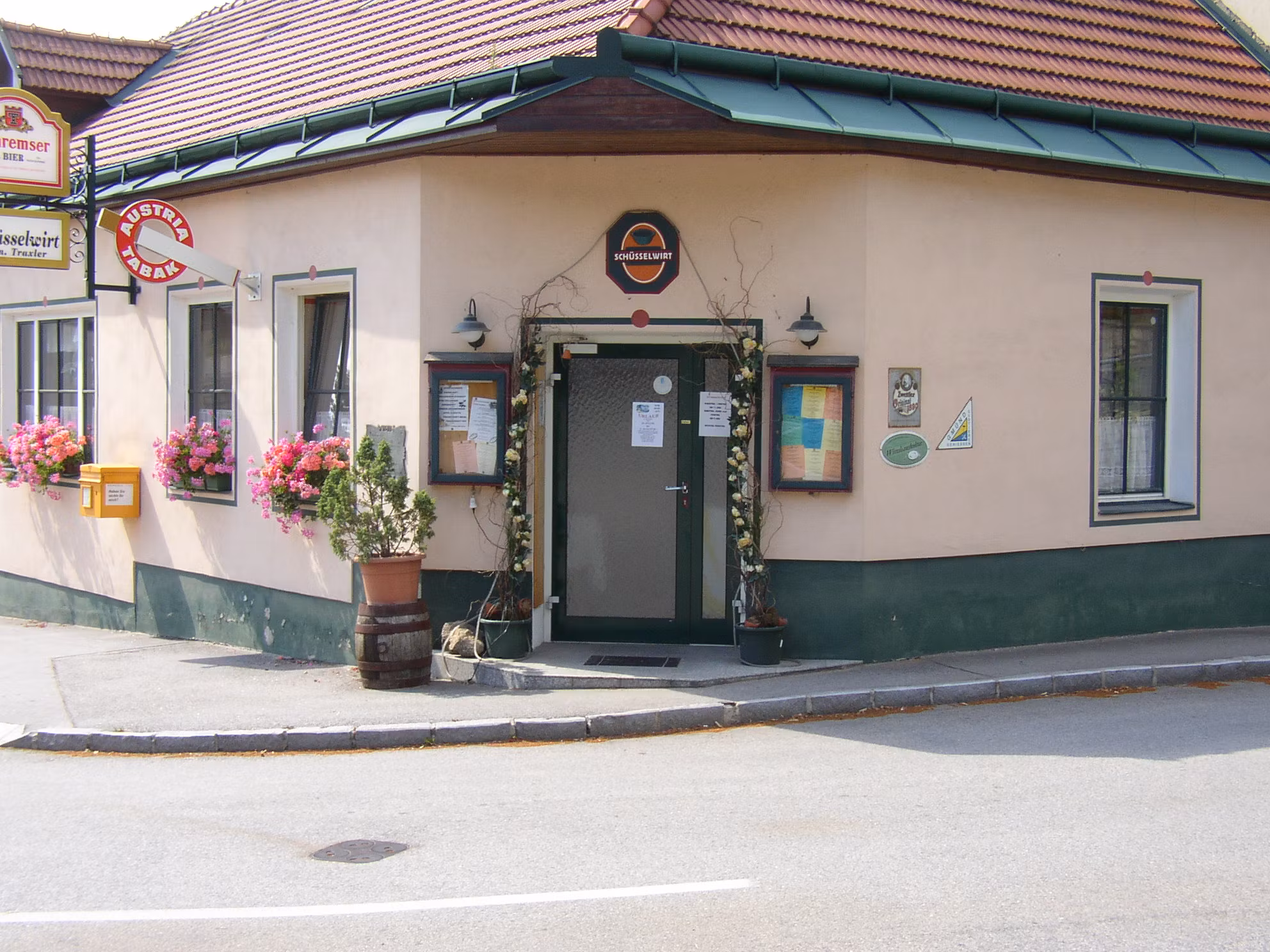 Eingang eines traditionellen Gasthauses mit Blumen und Schildern.