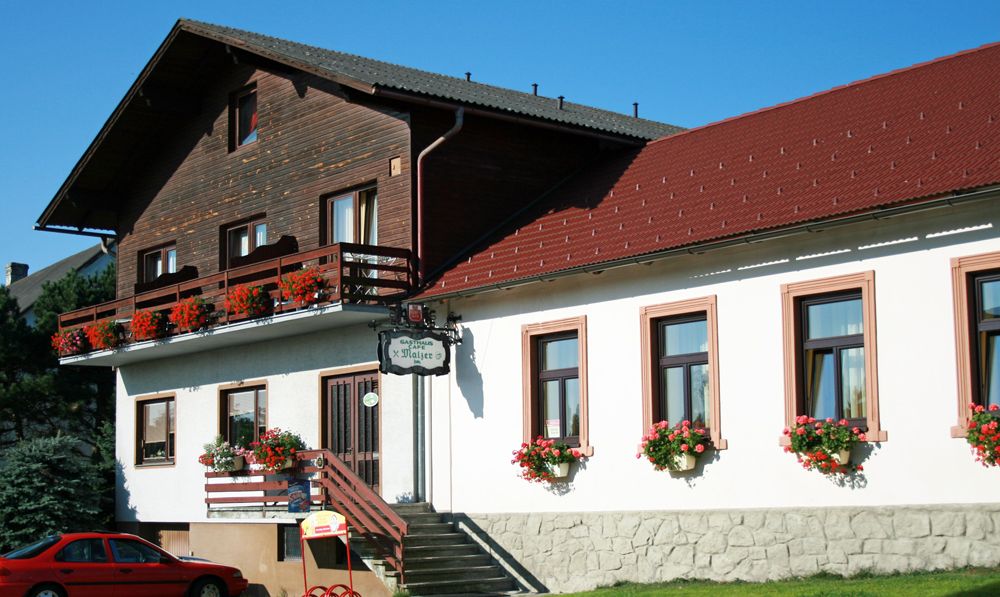 Gasthaus Malzer mit Blumen geschmücktem Balkon und Fenstern.