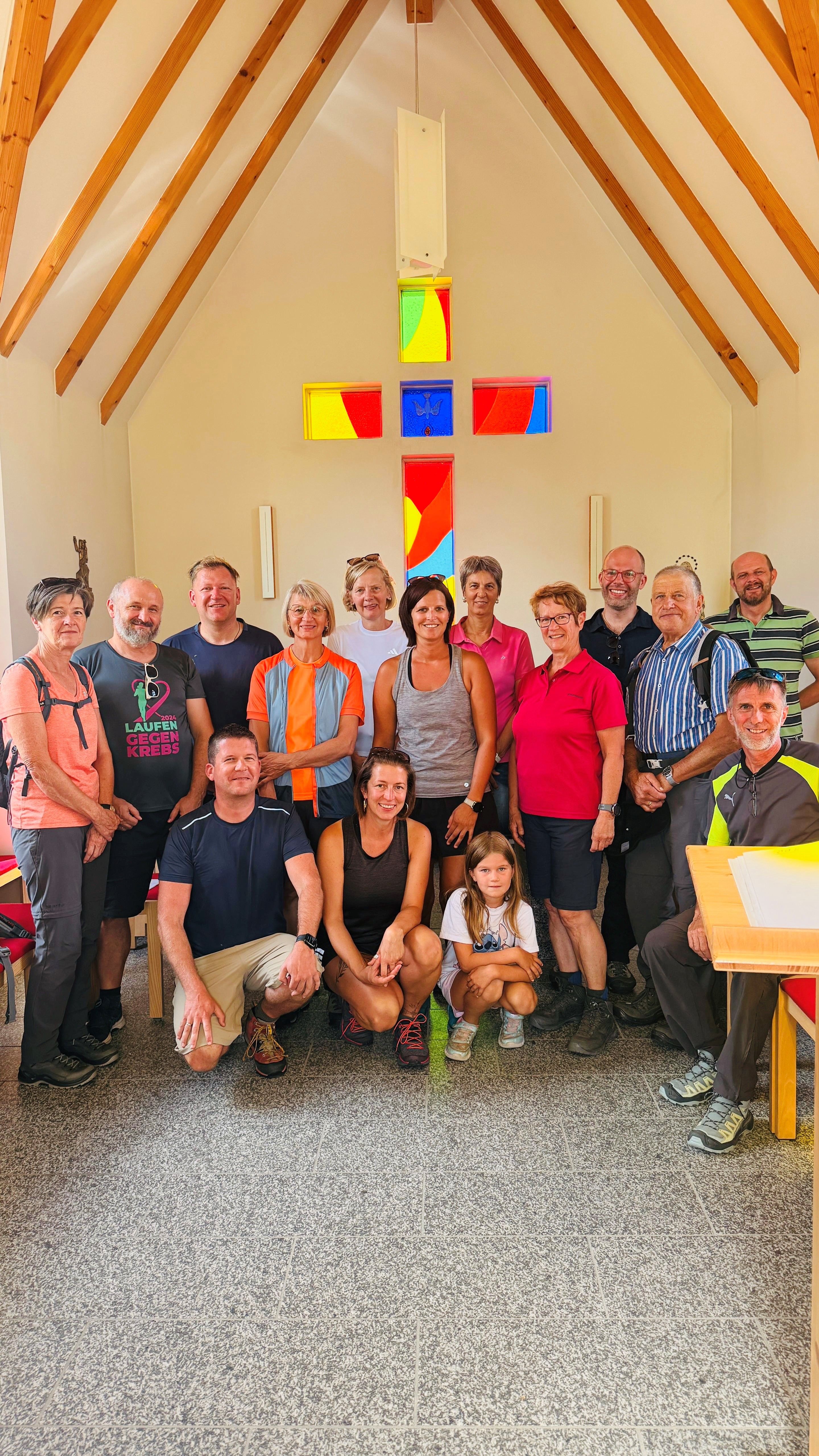 Eine Gruppe von Menschen in einer Kapelle unterhalb eines bunten Glases.
