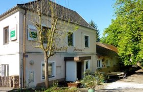 Ein traditionelles Gasthaus mit weißer Fassade und grünen Bäumen im Hintergrund.