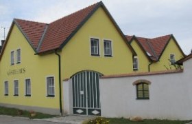 Gelbes Gebäude mit rotem Dach und grünen Toren, beschriftet mit 'Gästehaus'.