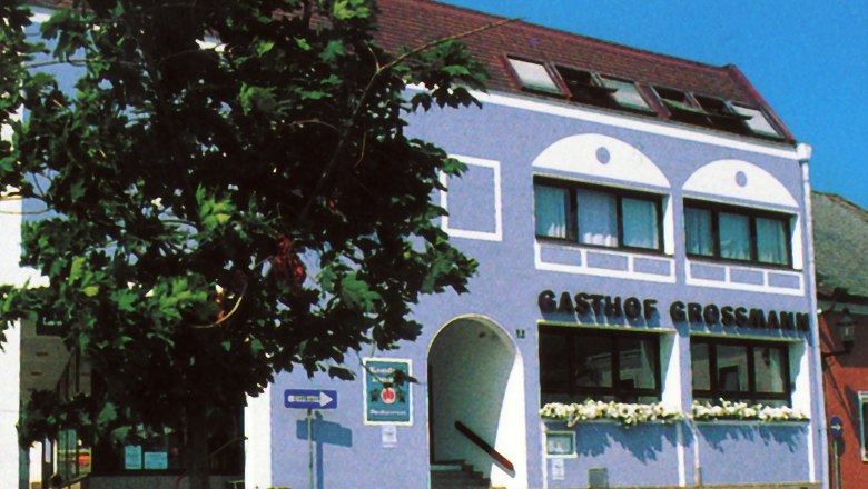Gasthof Großmann mit blauer Fassade und Baum im Vordergrund.