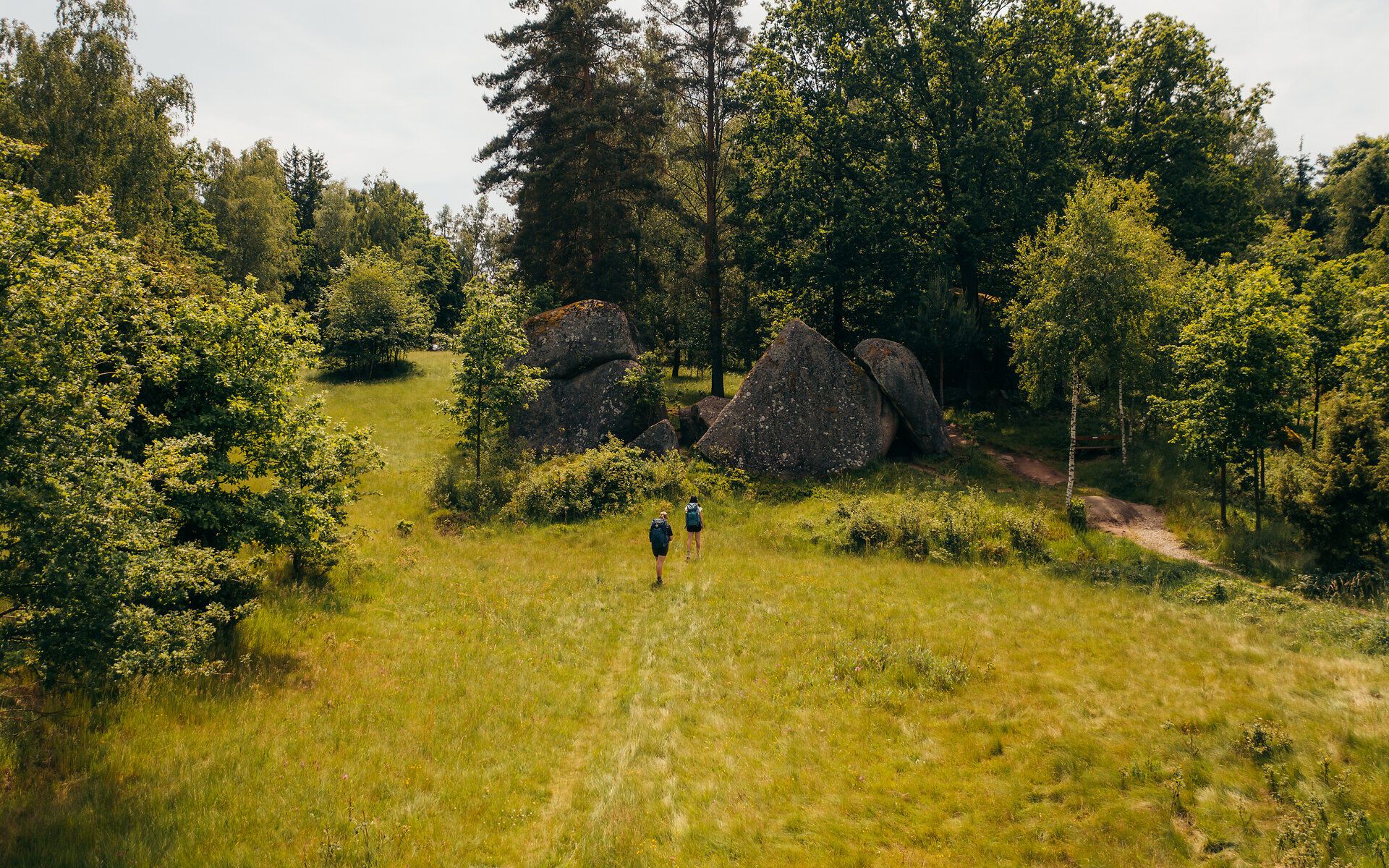 Zwei Personen gehen auf die Steinformationen in der Blockheide zu