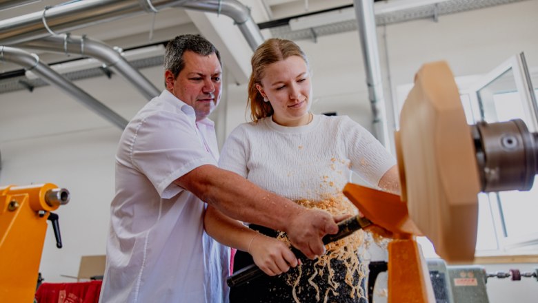 Ein Mann und eine Frau arbeiten gemeinsam an einer Drechselmaschine.