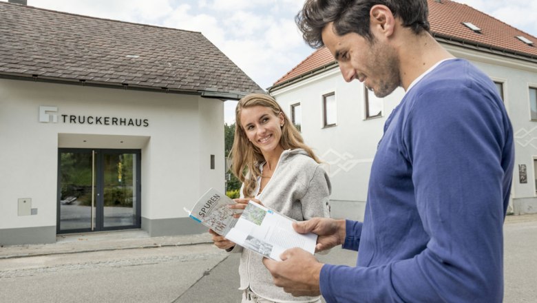 Zwei Personen vor dem Truckerhaus, die Broschüren lesen.