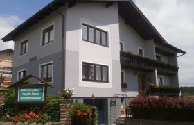 Ein zweistöckiges Gästehaus mit Balkon und Garten.