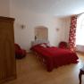 Ein gemütliches Schlafzimmer mit rotem Bett, roten Vorhängen und Holzmöbeln.