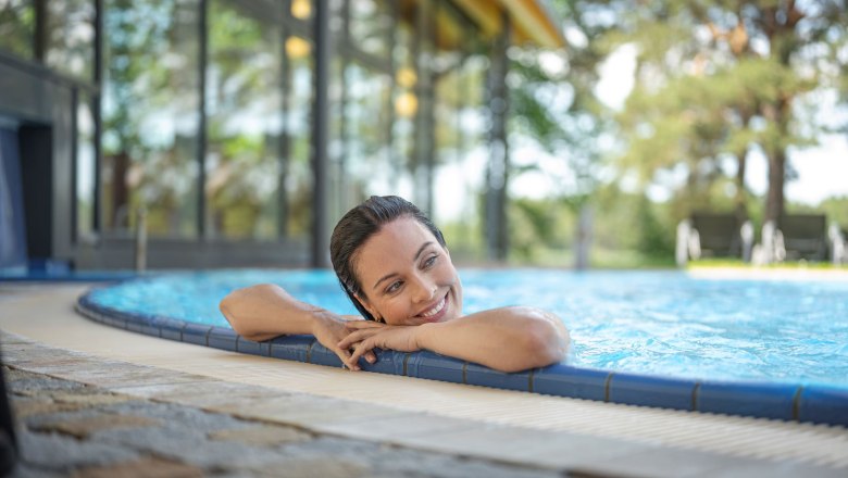 Frau entspannt im Pool am Beckenrand.