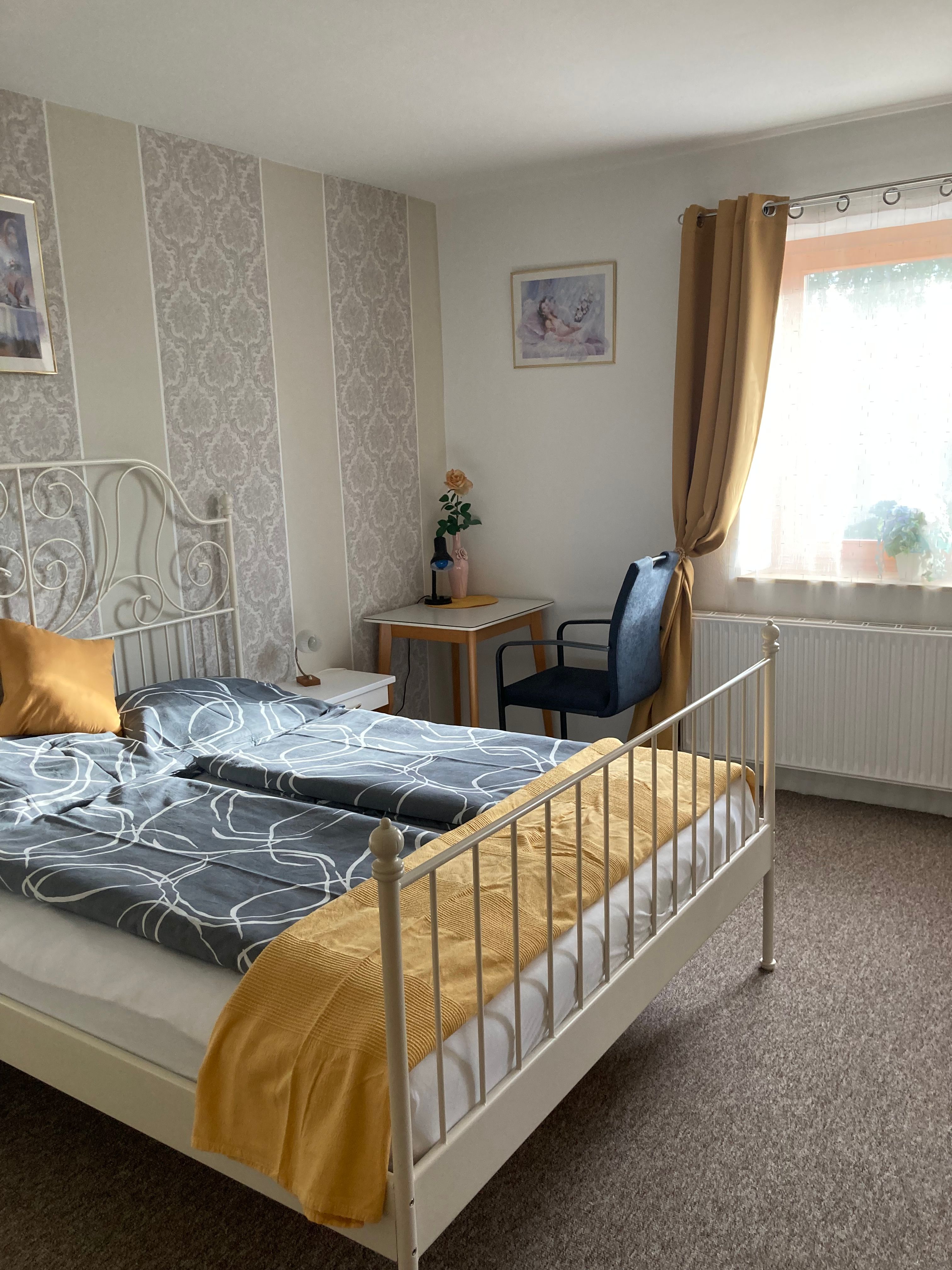 Gemütliches Schlafzimmer mit Doppelbett, gelben Vorhängen und dekorativer Tapete.