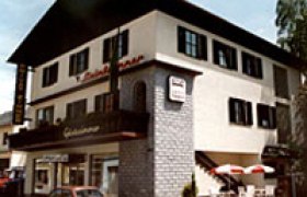 Ein zweistöckiges Gebäude mit Balkon und Terrasse, beschriftet mit 'Steinbrunner'.